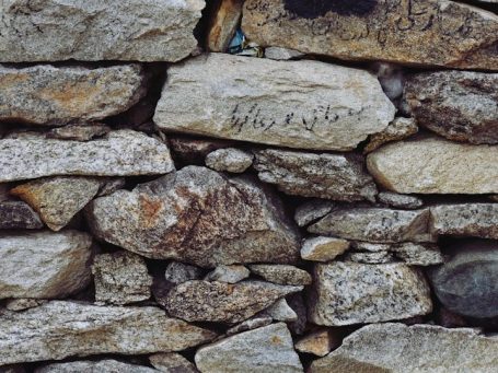 Mauer aus unterschiedlich großen Steinen mit grauen und braunen Tönen.