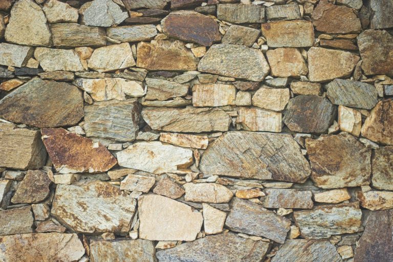 Gemauer aus unregelmäßigen, graubraunen Steinen mit unterschiedlichen Texturen.