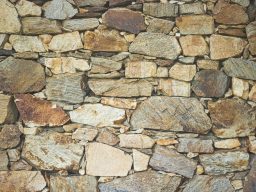 Eine Mauer aus unregelmäßigen, groben Steinen in verschiedenen Farben und Größen.
