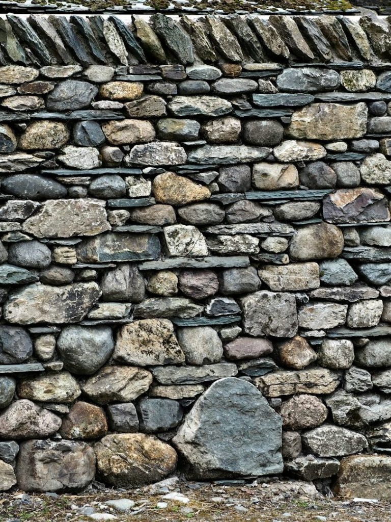 Eine strukturierte Steinmauer mit unterschiedlichen Steingrößen und Farben.