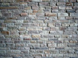 Mauer aus unregelmäßigen, grauen und braunen Ziegelsteinen.