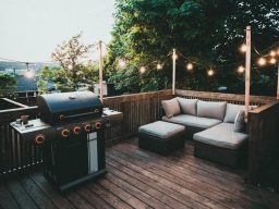Gemütlicher Außenbereich mit Grill und Sitzgelegenheiten, umgeben von Lichtern und Bäumen.