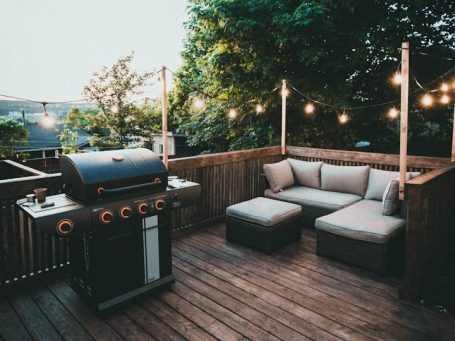 Gemütlicher Außenbereich mit Grill und einer Sitzgruppe, umgeben von Lichtern.