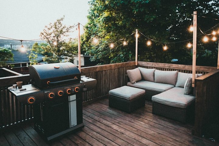 Gemütlicher Außenbereich mit Grill und Sitzgelegenheit, umgeben von Lichtern und Bäumen.